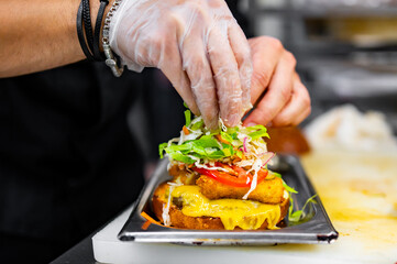 chef hand cooking burger with vegetables and meat on restaurant kitchen