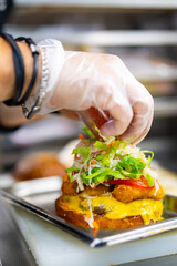 chef hand cooking burger with vegetables and meat on restaurant kitchen