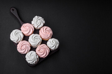 Delicious sweet multi-colored marshmallow on a dark concrete background