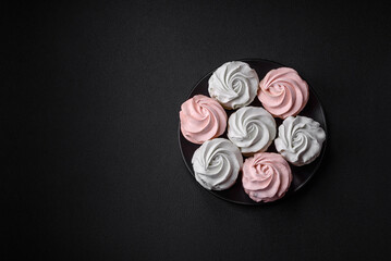 Delicious sweet multi-colored marshmallow on a dark concrete background