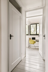 Fototapeta na wymiar a hallway with white walls and wood flooring the door is open to an office area that has a yellow chair