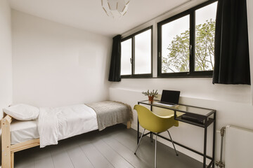 a bedroom with a bed, desk and window overlooking the cityscapearn com logo on the wall