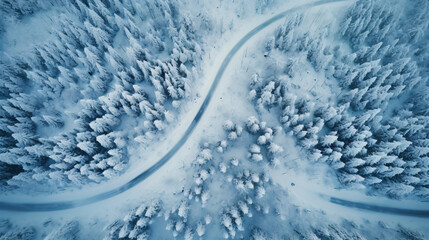 Windy and curvy road in snow covered forest landscape, top down aerial view.