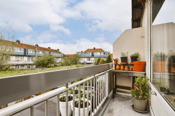 a balcony with potted plants on the railings and houses in the background, taken from an apartment balcony