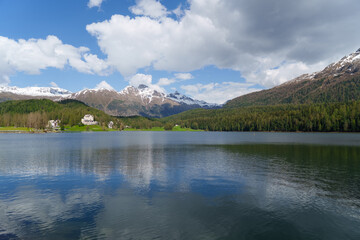Snow-covered mountains, clear lakes, lakeside houses and coniferous forests. St. Moritz Retreat: Capturing the Scenic Landscapes of a Swiss Vacation Town.