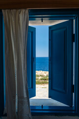 The view at the sea from an open traditional blue window with blue half open shutters , Ayia Napa,...