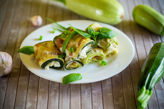 cooked zucchini rolls with cheese filling inside, in a plate