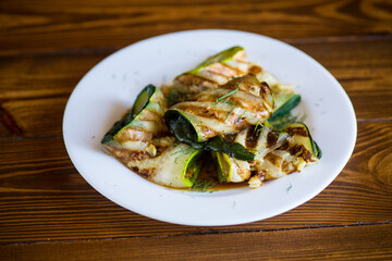 Grilled zucchini pieces with garlic sauce in a white plate.