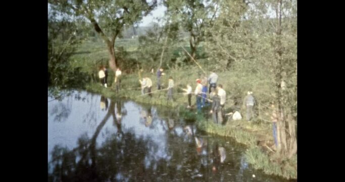 Fishermen fishing lake on green park background. People holding fishing rods, catch fish in river. Summer hobby leisure in nature. Recreation in vacation. Archival vintage color film. Archive travel