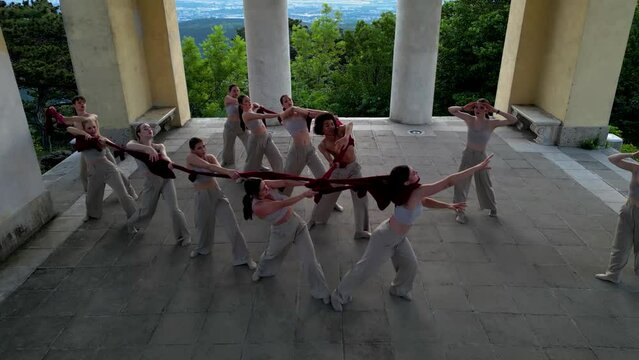 Group of dancers performing an interpretive dance in a temple, aerial view, 4k
