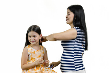 Young brunette asian mother is combing hair of her little daughter. Isolated on white.