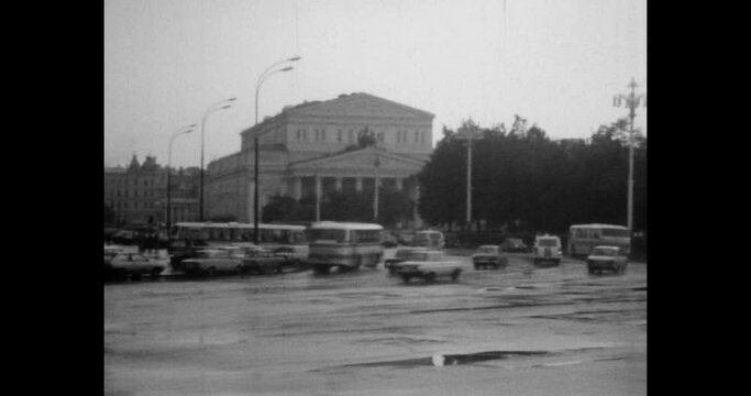 Cars moving fast speed in city street. Rush hour in town center. Urban road traffic. Transport motion on cityscape background. Archival vintage black white film. Old retro archive. 1980s Moscow Russia