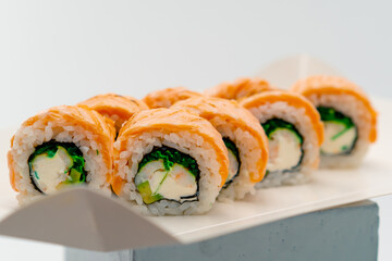 Close-up of a philladelphia roll with salmon cucumber and cottage cheese on a white background in a sushi box 