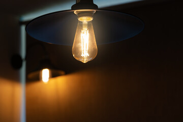 vintage electric lamp with a retro-style shade illuminates an old brick wall, loft