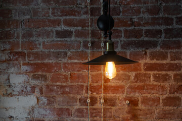vintage electric lamp with a retro-style shade illuminates an old brick wall, loft