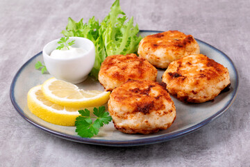 Cutlets with codfish and shrimps served with salad leaves, lemon and sour cream sauce on the plate - 626914792