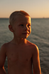 Fototapeta na wymiar Portrait of a cute balkan blond boy at sunset by the sea