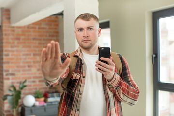 looking serious showing open palm making stop gesture. smartphone concept