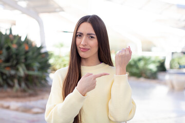 young pretty woman looking impatient and angry, pointing at watch, asking for punctuality, wants to be on time