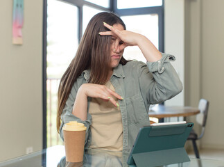 young pretty woman covering face with hand and putting other hand up front to stop camera, refusing...