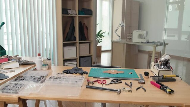 Medium shot of table in leather workshop with everything for crafting on it