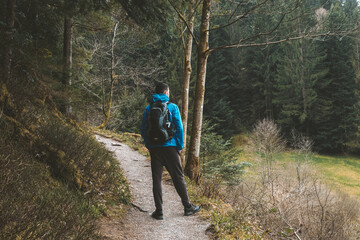 A guy tourist with a backpack stands on a mountain trail and looks into the distance. The concept of travel and adventure. Traveler Man with backpack mountaineering Travel Lifestyle concept mountains