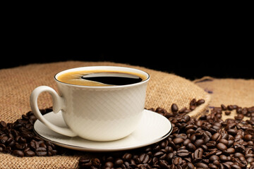 Black coffee or hot tea in a cappuccino espresso cup, breakfast food with coffee beans on a wooden table Isolated on a dark background, top view