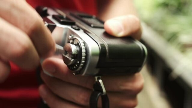 Photographer takes out the film rewind knob to open the back of his camera