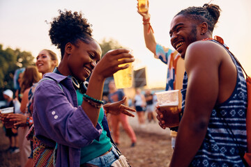 Happy black couple having fun and dancing during open air music concert during summer.