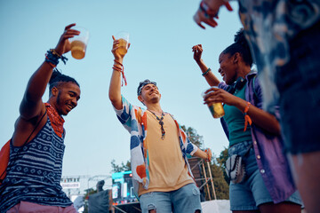 Multiracial group of young people dancing while attending summer music festival.