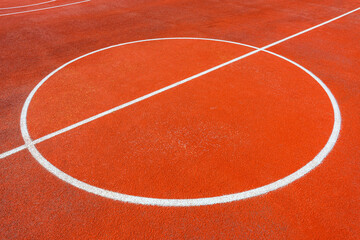 Minimalist abstract background of an orange tartan outdoor basketball court with white lines.