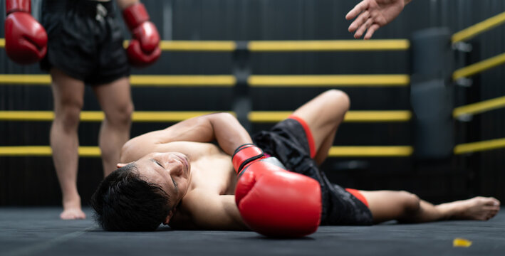 Unconscious Asian boxer lay on floor referee counting down knockout in the ring at fitness gym. Boxing is fighter sport training need body muscular strength, power fist and sweating to become champion