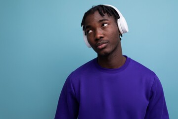 well-groomed african young brunette man with dreadlocks with wireless headphones