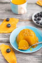 Mango and passion fruit jelly with blueberry on gray wooden, side view, selective focus.