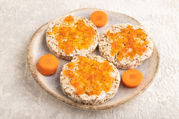 Carrot jam with puffed rice cakes on gray concrete. Side view.