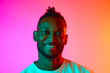 Portrait with smiling african man looking at camera over gradient colorful background in neon.