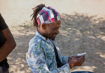 rasta man with dreadlocks in the village, reading a newspaper cut