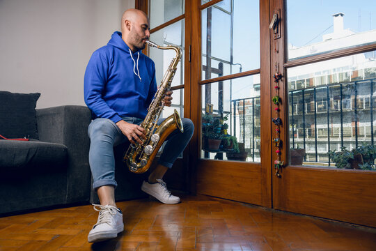 young latin man saxophonist playing inspired in his living room