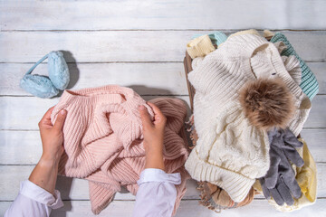 Preparation for fall and winter season, autumn warm cozy clothes, Stack of clean freshly laundered, neatly folded jackets, sweaters, blankets, hats, mittens in wooden box, taken from the mezzanine