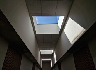 Obraz premium high above the head is a rectangular window illuminating the entire area of the hall with natural light. the window is a rectangular skylight. the walls are pure white plaster