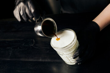 barista in latex gloves preparing latte macchiato, pouring espresso, pitcher with black coffee