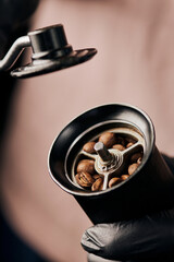 cropped view of barista holding manual coffee grinder with coffee beans, arabica, close up, energy