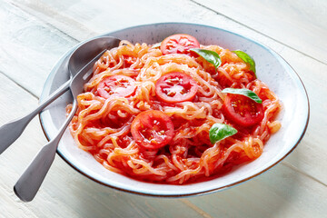 Konjac pasta. Shirataki noodles with tomato and basil, a healthy vegan dish, on a wooden background