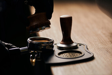 cropped view of barista holding tamper near portafilter with grinded coffee, espresso, professional