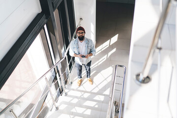 Man in denim outfit using mobile phone on stairs