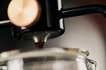 close up view of freshly brewed espresso dripping from siphon coffee maker, blurred foreground