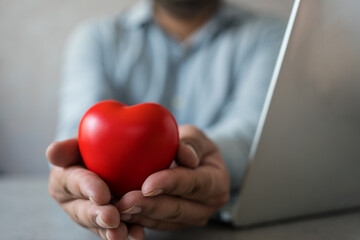 Hands cradling a red heart for health care, love and organ donation. Family insurance and CSR...