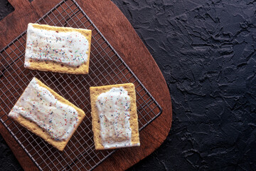 Pop tarts on a baking rack. Poptart toaster pastry with icing on a black background, overhead flat...