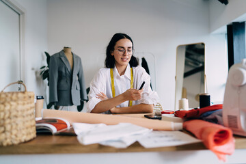 Positive female designer drawing sketches of clothes