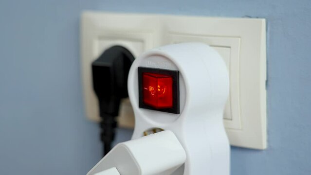 Turning on the red switch of the electrical splitter in wall outlet close up. Home power supply concept